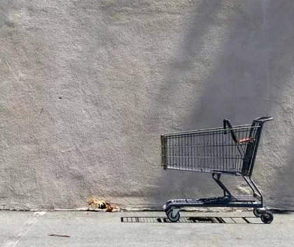 Empty shopping cart against a blank grey wall