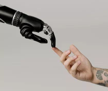 Human hand touching the a robot hand with its index finger 